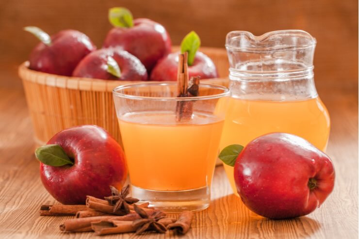 bicchiere e caraffa di aceto di mele, mele rosse e cannella