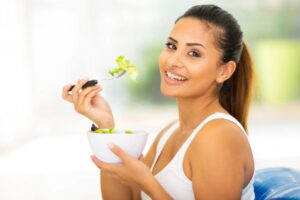 donna che sorride mentre mangia un'insalata