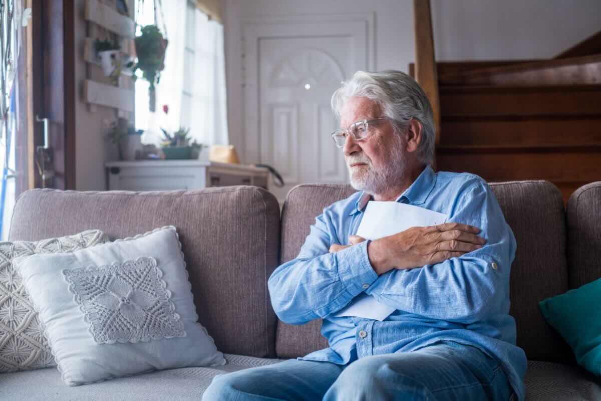 Uomo triste guarda nel vuoto abbracciando documento