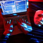 una persona che fa una truffa con il computer ed una maschera bianca vicino