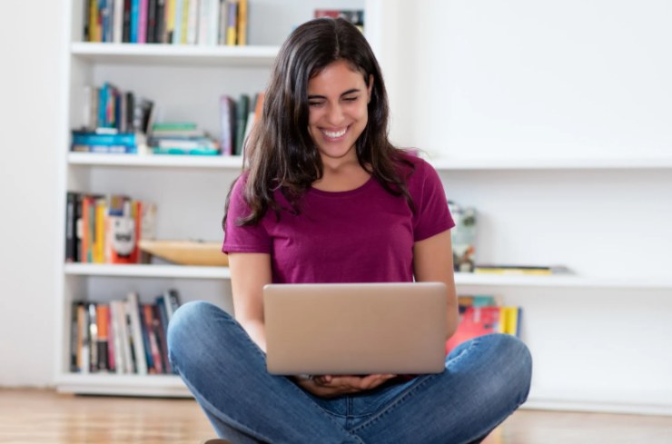 donna che sorride seduta sul pavimento con il computer sulle gambe