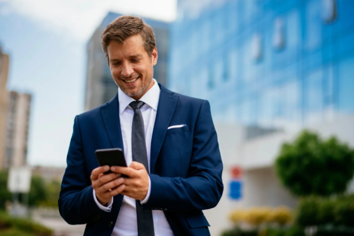 uomo in giacca e cravatta con in mano il cellulare